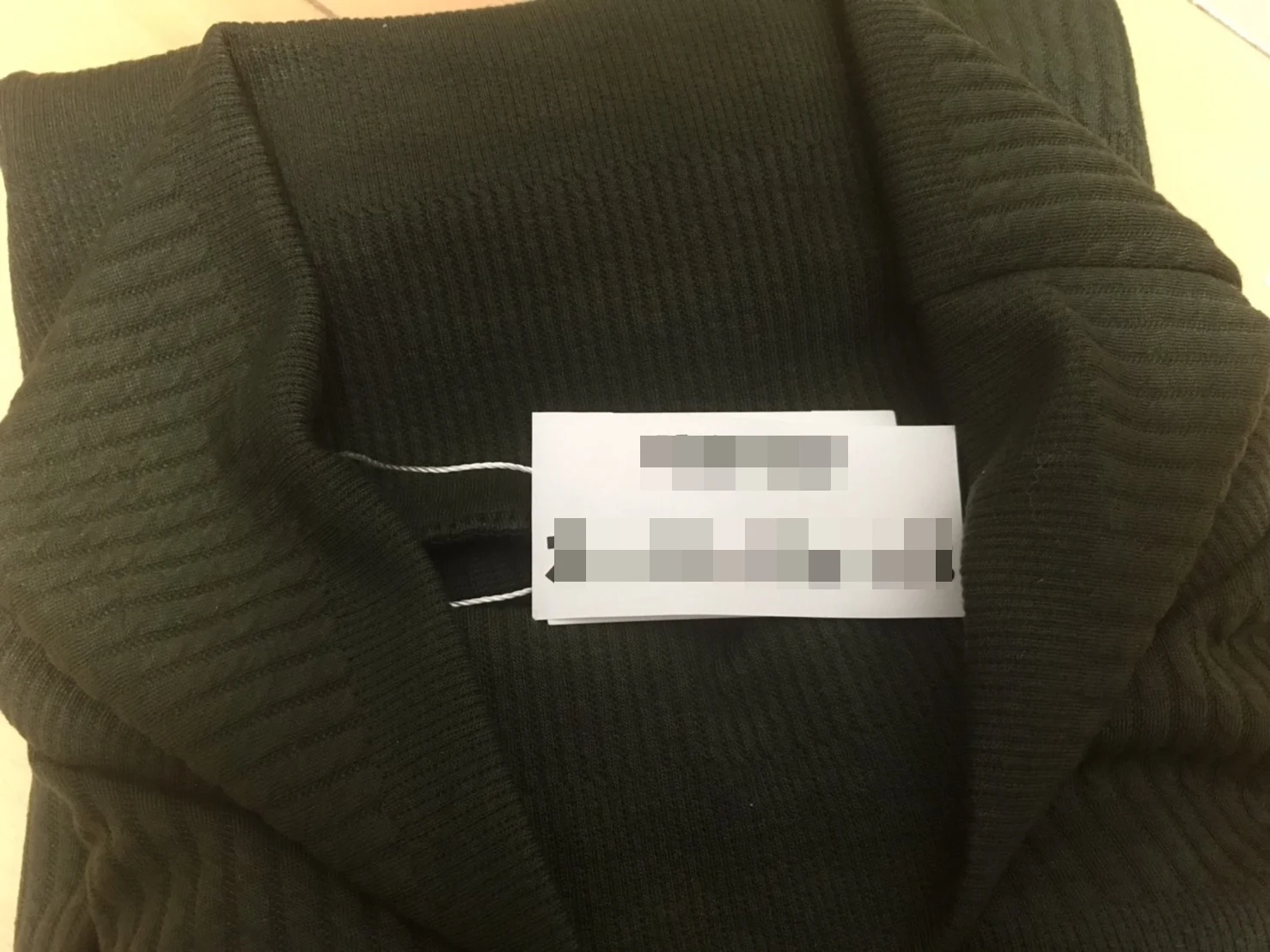ブランド名を印刷した紙タグを服に乗せて撮影した商品画像(ブランド名はモザイク)